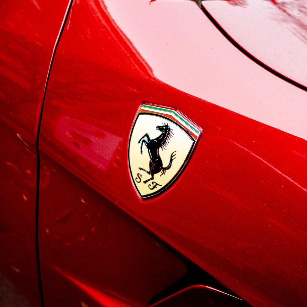 primissimo piano di uno stemma Ferrari su una macchina Ferrari rosso fuoco