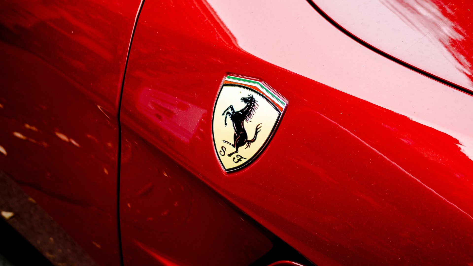 primissimo piano di uno stemma Ferrari su una macchina Ferrari rosso fuoco