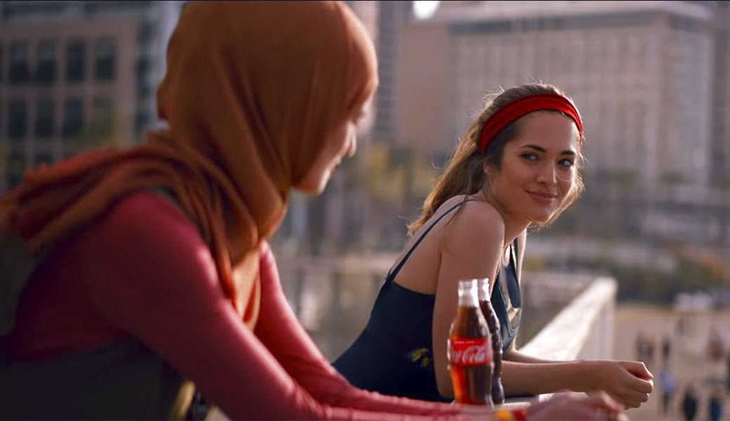 Due donne condividono una Coca Cola al tramonto